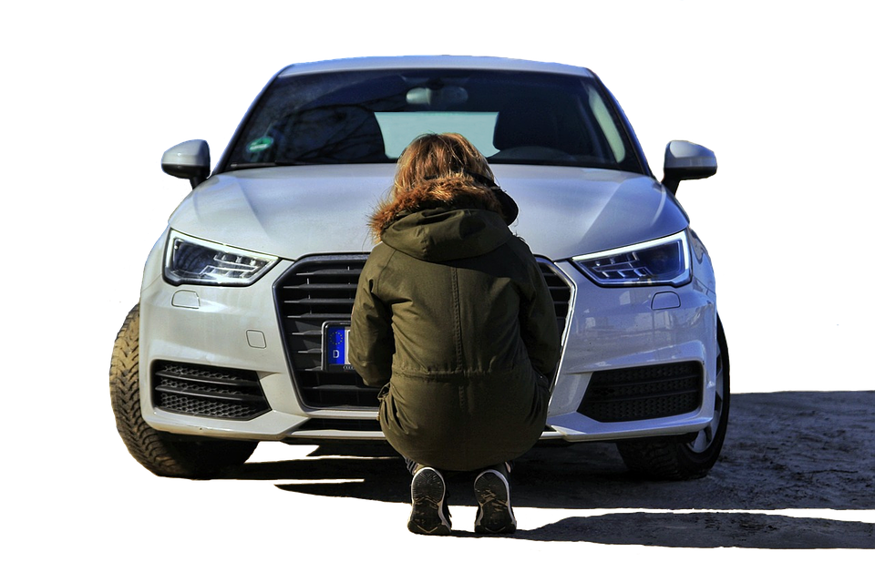 A Woman Kneeling In Front Of A Car