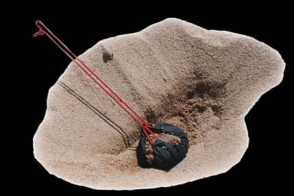 A Bag With Red Ropes In Sand