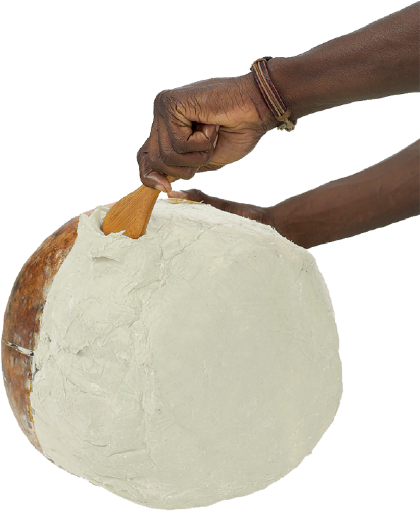 A Person's Hand Holding A Wooden Spoon Over A Round White Object