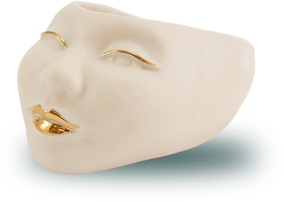 A White Ceramic Face With Gold Paint On It