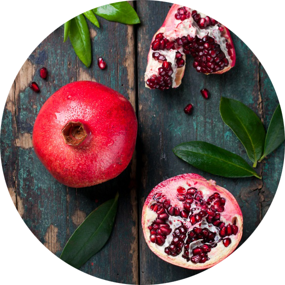 A Pomegranate Cut In Half With Leaves On A Table