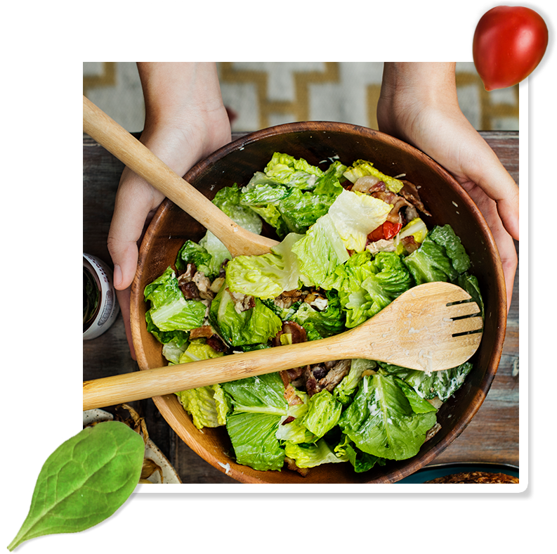 A Bowl Of Salad With Wooden Spoons