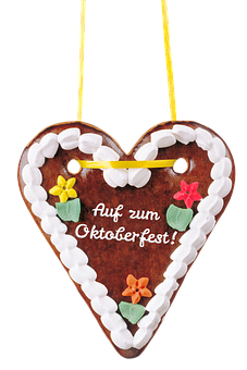 A Gingerbread Heart With White Frosting And Flowers