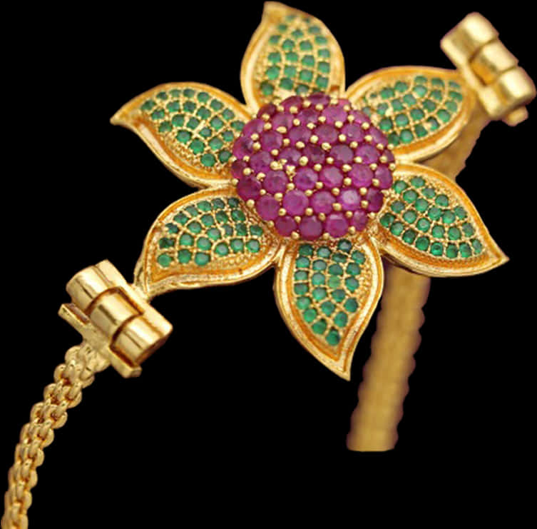 A Gold Bracelet With A Flower And Green Leaves