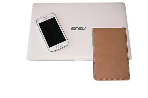 A White Laptop With A Cell Phone And A Brown Wallet