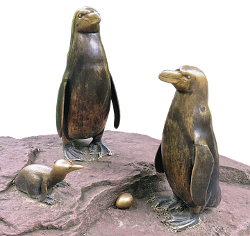 A Statue Of Penguins And A Baby Penguin