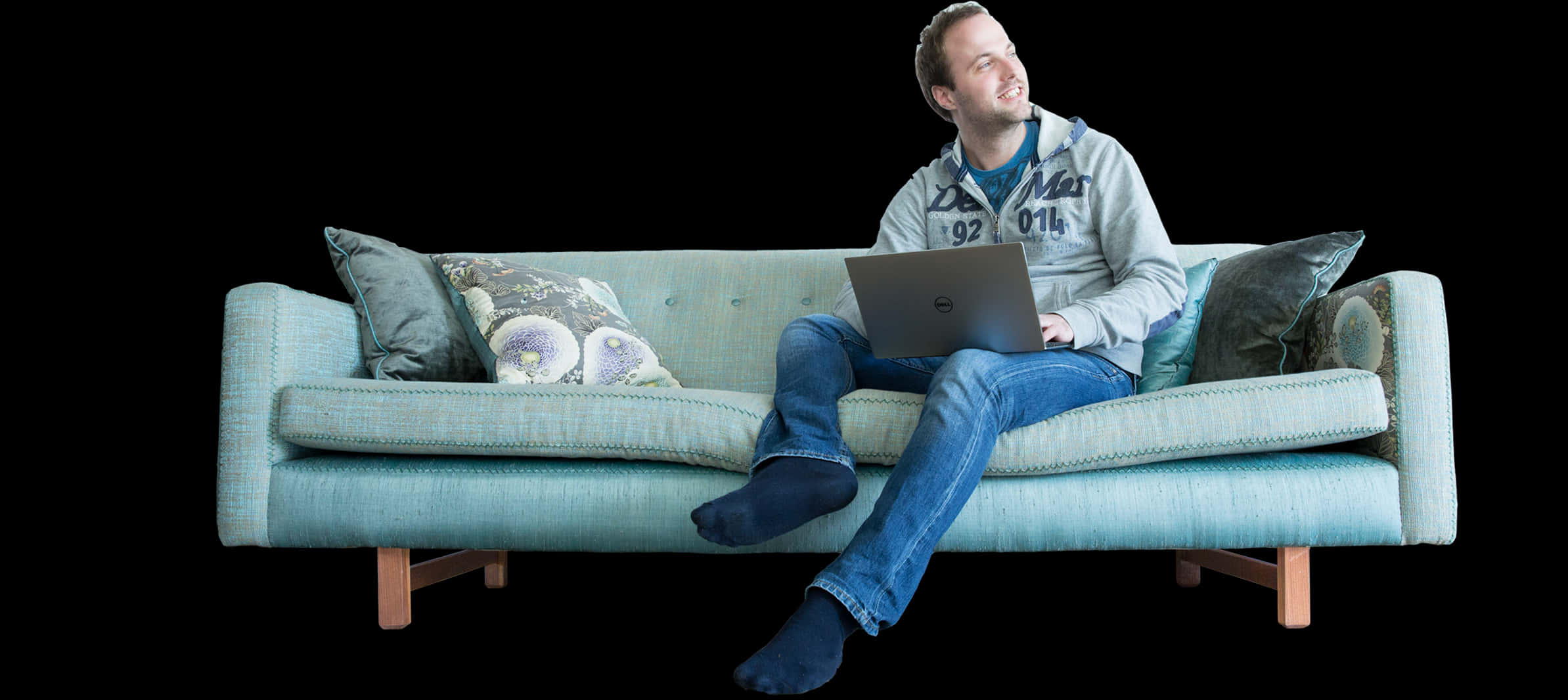 A Man Sitting On A Couch With A Laptop