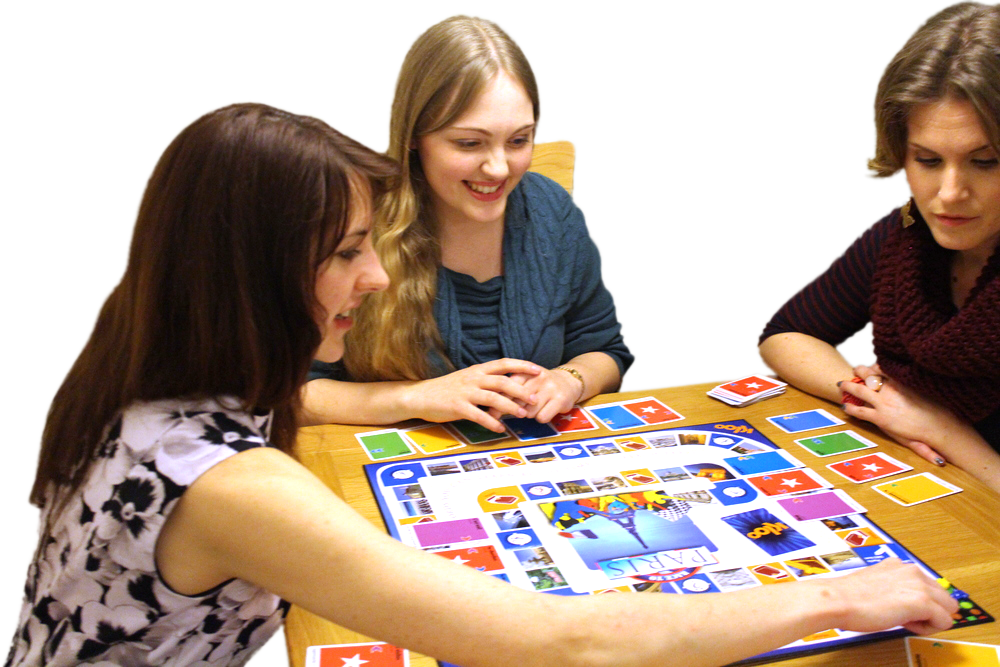 A Group Of Women Sitting At A Table Playing A Board Game
