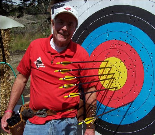 A Man Holding Arrows In Front Of A Target