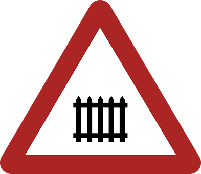 A Red And White Triangle Sign With A Black Fence