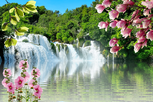 A Waterfall Surrounded By Trees And Flowers